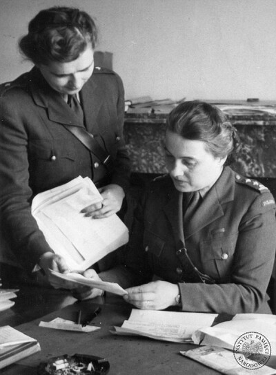 IPNBU-2-6-118-3 Zastępczyni komendantki głównej Pomocniczej Służby Kobiet Polskich Sił Zbrojnych na Zachodzie (1942-43) i p.o. komendantki głównej (od 1943 r.) płk Maria Leśniakowa zapoznaje się z dokumentem podany przez nieznaną z nazwiska podwładną - widok w gabinecie za biurkiem.