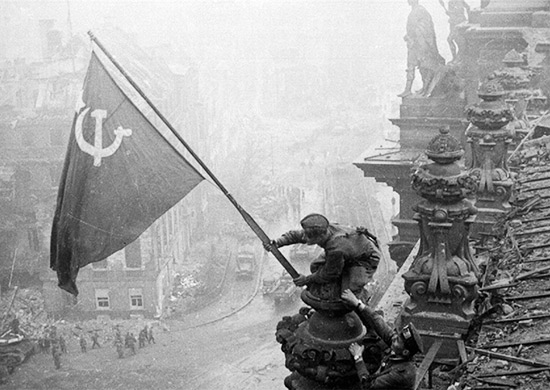Czerwonoarmiści wywieszający flagę ZSRR na dachu Reichstagu. Zdjęcie wykonał Jewgienij Chałdiej.