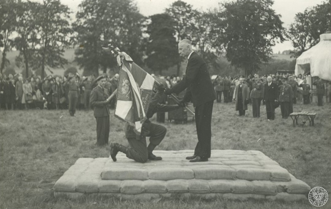 Prezydent RP na Wychodźstwie Władysław Raczkiewicz (stoi po prawej) wręcza ufundowany w kraju sztandar 1. Samodzielnej Brygadzie Spadochronowej, 15 czerwca 1944, Cupar (Wielka Brytania). Fot. z zasobu IPN