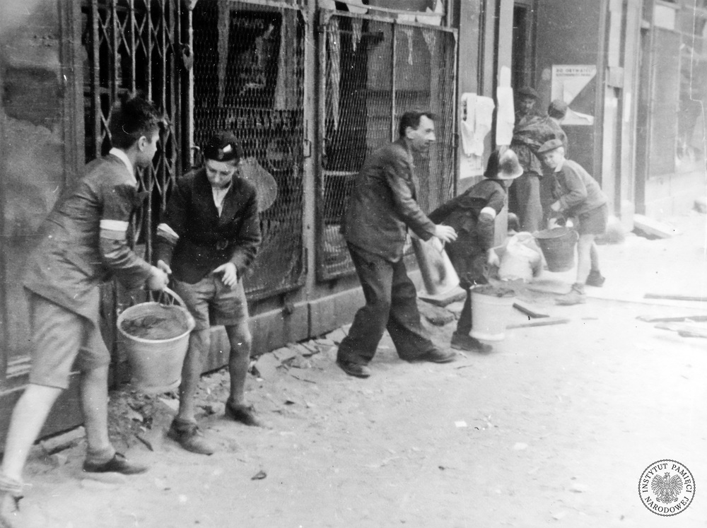 Chłopcy podający wodę podczas gaszenia pożaru (fot. z zasobu AIPN)