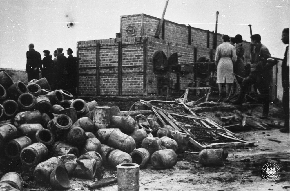 Obóz na Majdanku po wyzwoleniu. Na zdjęciu na pierwszym planie urny na prochy zmarłych, dalej widoczni od tyłu żołnierze i osoby cywilne oglądający piece do kremacji zwłok. Lublin, lipiec 1944 r. Fot. z zasobu AIPN