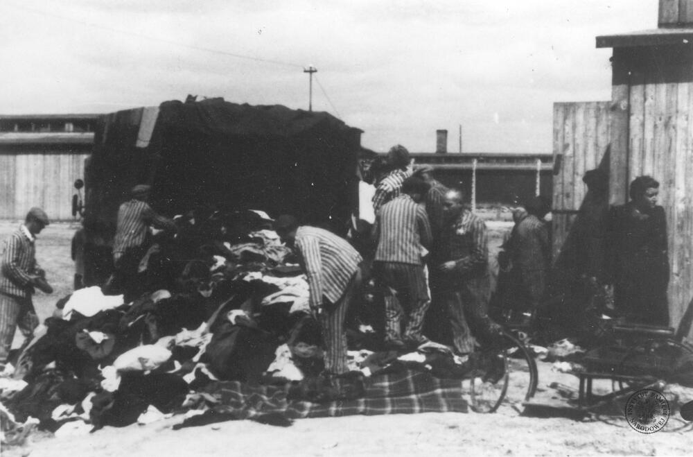 syg. GK-9-1-42-175, Więźniowie wypakowują przywiezione przez samochód ciężarowy mienie i rzeczy osobiste pozostałe po przybyciu transportu Żydów z Węgier(?) w obozie zagłady KL Auschwitz-Birkenau. Autor: Hoffmann E. - plutonowy SS, Walter B. - starszy sierżant SS. Źródło AIPN.
