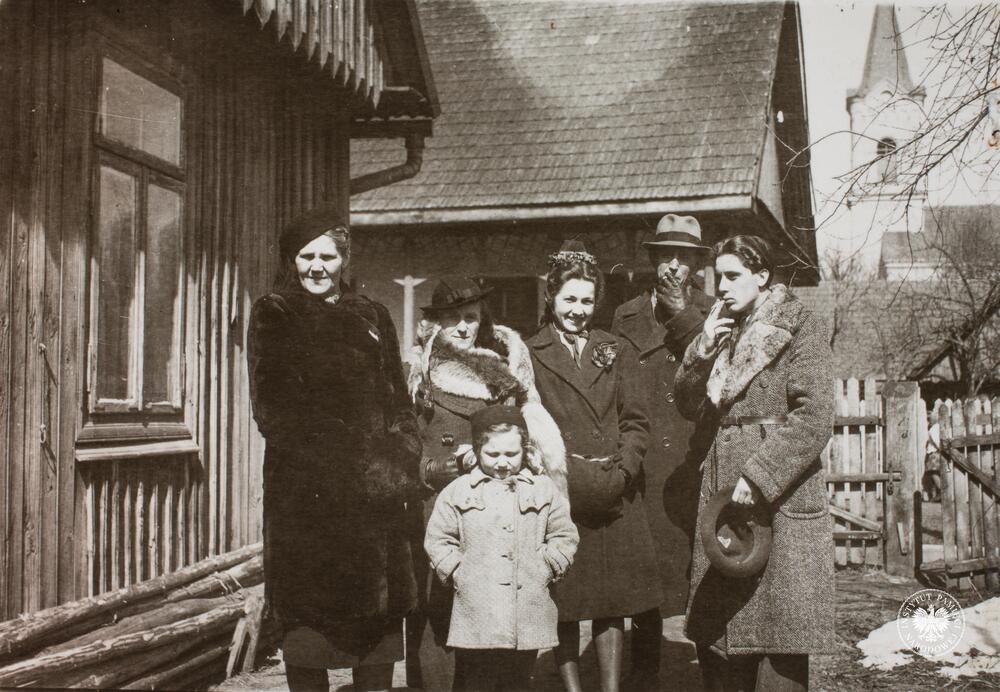 Od lewej: NN, Maria Gajda z d. Łuczak, na dole NN dziecko, w środku Jadwiga Naja – od 1944 r. Gajda, NN, Tadeusz Gajda. Na drugim planie widoczny kościół parafialny w Nisku. Na odwrocie zdjęcia zapisek 5 IV 1942, fot. AIPN, sygn. IPNRz-13-1-399-5-1