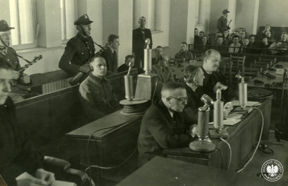 Rudolf Höss (pośrodku, w słuchawkach), były komendant KL Auschwitz-Birkenau, siedzi na ławie oskarżonych w czasie swojego procesu przed Najwyższym Trybunałem Narodowym, marzec 1947. W pierwszym rzędzie siedzą m.in. obrońcy z urzędu Tadeusz Ostarzewski i Franciszek Umbreit. Fot. z zasobu IPN