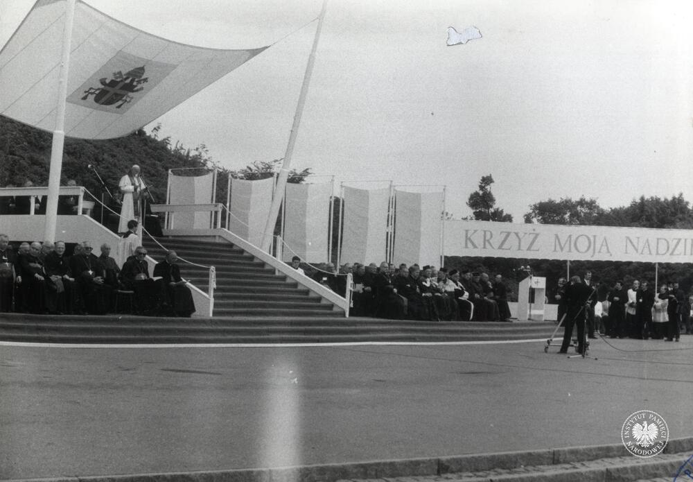 Trzecia pielgrzymka Jana Pawła II do Polski. Papież Jan Paweł II na Westerplatte w czasie wizyty w Polsce w 1987 r. Na transparencie napis: „Krzyż moją Nadzi[eją]”, 12 czerwca 1987 r.,  z zasobu AIPN, sygn.  IPNGd-7-2-2-13-1