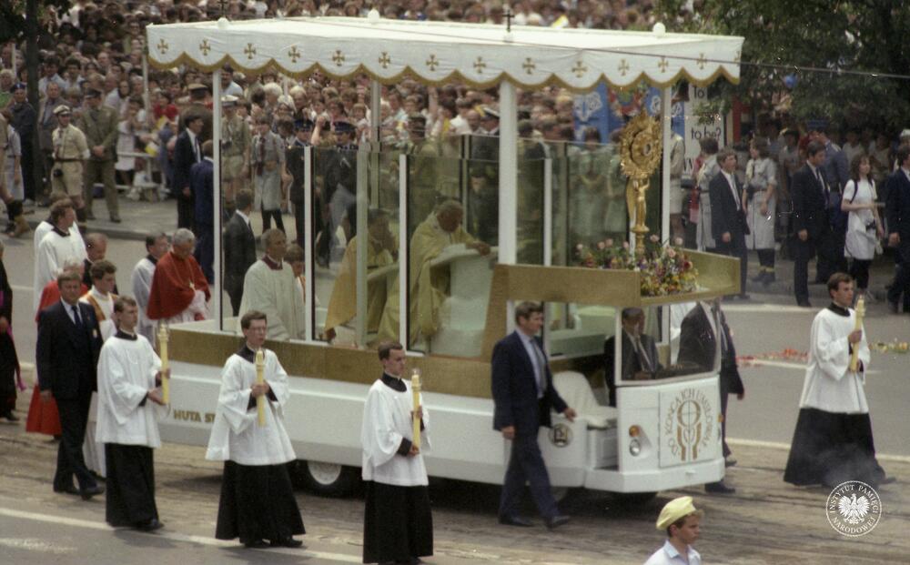 Trzecia pielgrzymka Jana Pawła II do Polski. Jan Paweł II klęczy w samochodzie przed monstrancją z Najświętszym Sakramentem, ul. Marszałkowska w Warszawie. Obserwacja operacyjna w ramach operacji Zorza II prowadzona na ulicach Warszawy w czasie trzeciej pielgrzymki papieża Jana Pawła II do Polski, z zasobu AIPN, sygn.  IPNBU-11-5-10-576-1