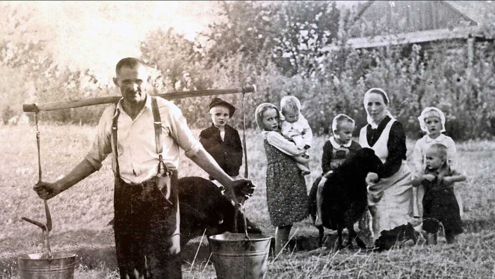 Kolaż dwóch zdjęć. Od lewej: Józef Ulma, Władzio, Stasia trzymająca na rękach Marysię, Franio, Wiktoria będąca w ciąży, Basia, a przed nią Antoś. W oddali po prawej chata Ulmów, gdzie na strychu ukrywali się Gołda Grünfeld, Lea Didner z córeczką Reszlą oraz Saul, Baruch, Mechel, Joachim i Mojżesz Goldmanowie. Stopklatka z prezentacji multimedialnej do wystawy „»Błogosławieni Sprawiedliwi, albowiem…« Opowieść o Rodzinie Ulmów” (wykonanie kompozycji: Kłaput Project w 2023 r.)