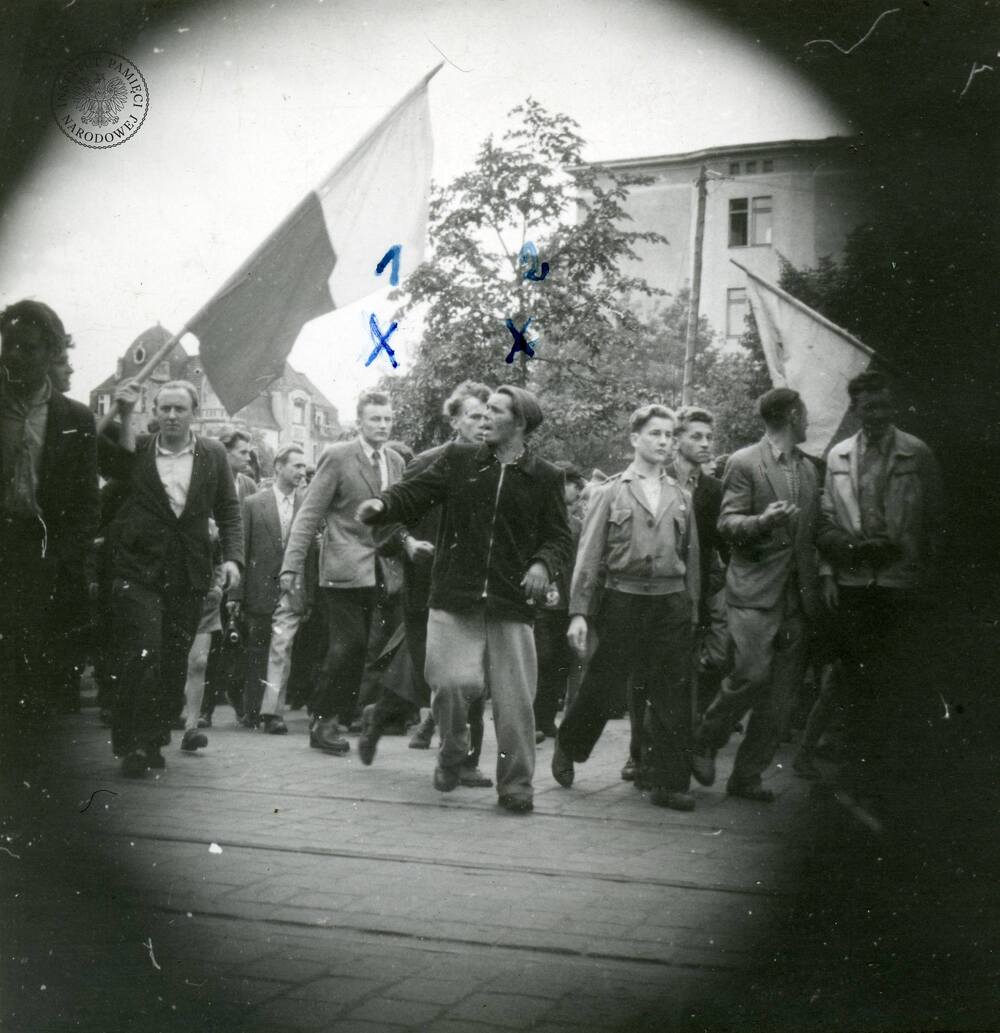 Pochód demonstrantów z biało-czerwonymi flagami prawdopodobnie na ul. J.H. Dąbrowskiego. Zdjęcie wykonane potajemnie z modelu fotograficznego - rogi zdjęcia zaciemnione. Poznań, 28 VI 1956 r. (fot. z zasobu IPN)