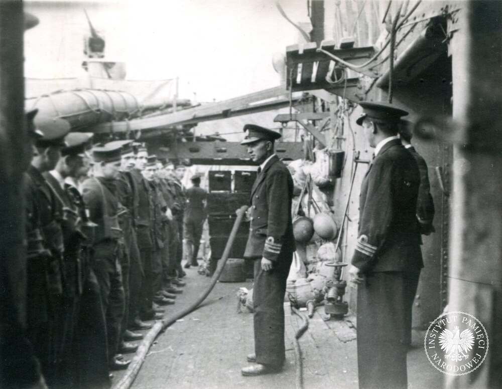 Kmdr por. Dzienisiewicz przemawia do załogi przed operacją lądowania w Normandii, czerwiec 1944 r. W operacji Neptune – fazie desantu z morza – wzięło udział ponad 1200 okrętów, 4100 jednostek desantowych, 1600 okrętów pomocniczych i statków handlowych. Wśród nich – oprócz Dragona – znalazły się cztery polskie niszczyciele: Błyskawica, Piorun, Ślązak i Krakowiak oraz polskie statki transportowe. Kopia cyfrowa ze zbiorów Stowarzyszenia Weteranów Armii Polskiej w Ameryce (z zasobu IPN)