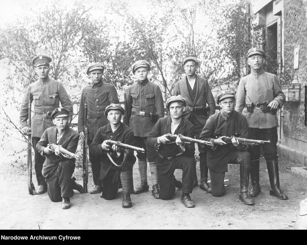 Grupa powstańców - 1. z prawej ma zatknięty za pas pistolet Mauser C96, klęczący 1. i 2. z prawej karabiny Mauser Gew98. Fot. NAC