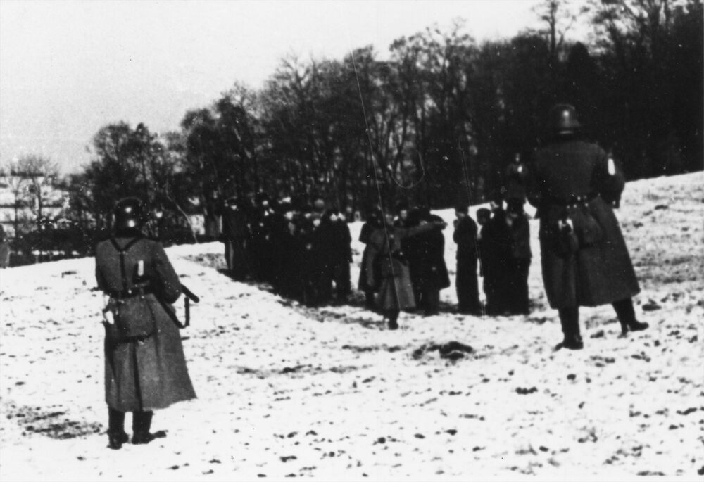 Fotografia przedstawia grupę kilkudziesięciu mieszkańców Bochni, na skraju lasku Uzbornia, pilnowanych przez żołnierzy niemieckich, na chwilę przed wykonaniem egzekucji. Fotokopia albumu "Sühne für Bochnia 18.12.1939" ["Kara dla Bochni 18 XII 1939"]. Fot. AIPN