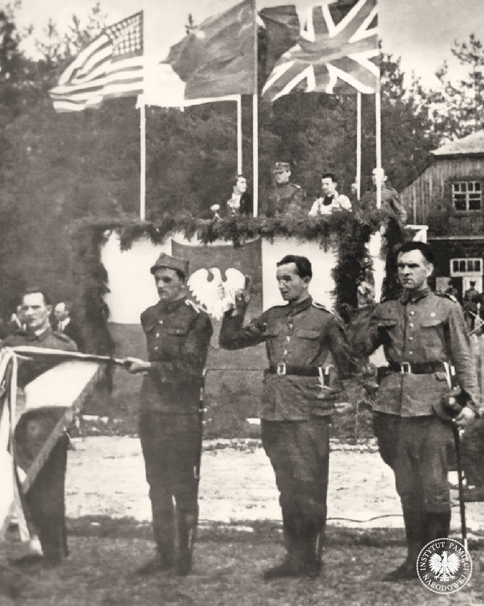 Przysięga 1 Warszawskiej Dywizji Piechoty im. Tadeusza Kościuszki w Sielcach nad Oką (ZSRS). Na trybunie honorowej od lewej: Wanda Wasilewska i Zygmunt Berling. Nad trybuną flagi: amerykańska, sowiecka i brytyjska; 15 VII 1943 r. (fot. z zasobu IPN)