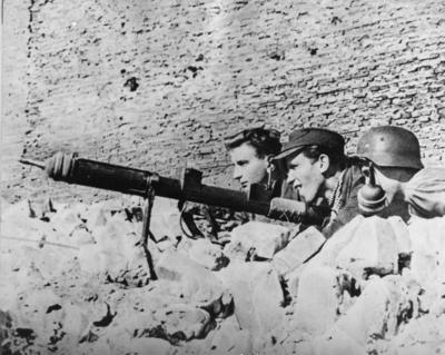 Powstańcy na stanowisku ogniowym, uzbrojeni w granatnik przeciwpancerny typu PIAT, 1944 r. (fot. AIPN)