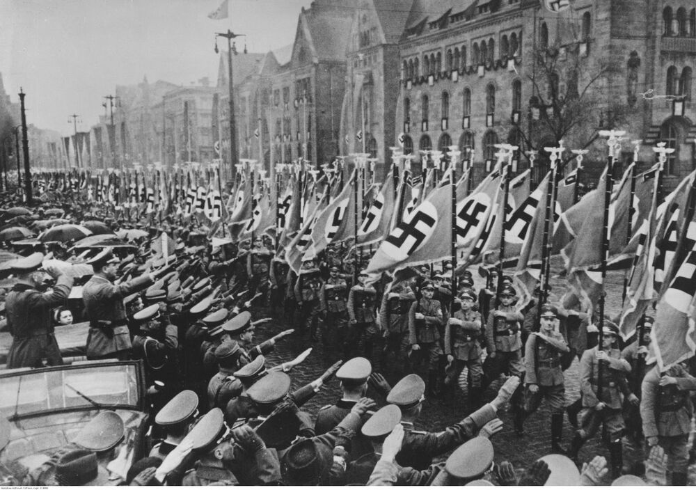 Przemarsz 517 chorążych niosących chorągwie lokalnych komórek NSDAP w Kraju Warty podczas poznańskich uroczystości drugiej rocznicy istnienia Reichsgau Wartheland. W kabriolecie po lewej stronie zdjęcia Arthur Greiser (źródło: Narodowe Archiwum Cyfrowe).