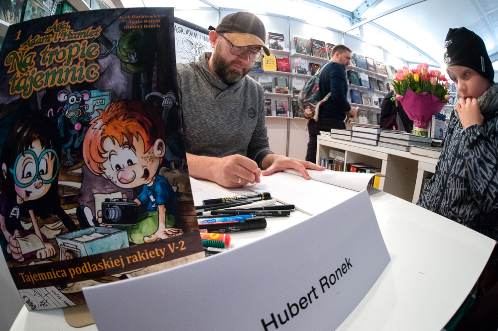 Hubert Ronek, twórca komiksowej serii #IPN „Wojenna odyseja Antka Srebrnego” rysuje i podpisuje – Targi Książki w Warszawie, 28 maja 2022. Fot. Sławek Kasper.