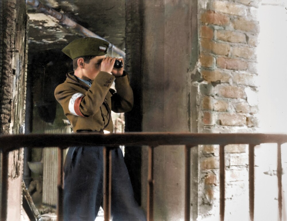 Do walki stanęły również warszawskie dzieci. Pełniły służbę jako łącznicy, przewodnicy w kanałach, niszczyły butelkami z benzyną niemieckie czołgi, z bronią w ręku pełniły służbę liniową na barykadach. Fot. Ze zbiorów Muzeum Powstania Warszawskiego, koloryzacja: Mikołaj Kaczmarek