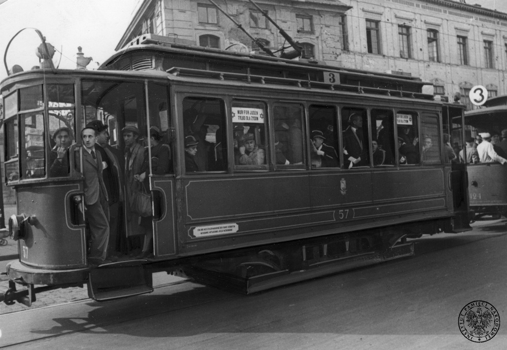 Niemieckie zdjęcie agencyjne z 1940 r. przedstawiające transport zbiorowy na ulicach getta w Warszawie. Na karcie zabezpieczającej umieszczono m.in. zdanie: „Do zarządzeń przeciwdziałających w Warszawie rozpowszechnianiu się epidemii, należy także tworzenie specjalnych wagonów tramwajowycyh dla Żydów, którzy z innych wagonów nie mogą korzystać”. Fot. z zasobu AIPN