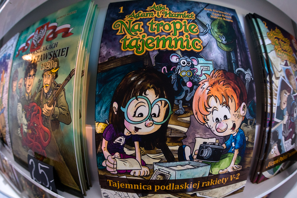 Hubert Ronek, twórca komiksowej serii IPN „Wojenna odyseja Antka Srebrnego” oraz „Aga, Adam i Hamlet na tropie tajemnic” rysuje i podpisuje – Targi Wydawców Katolickich w Warszawie, 23 kwietnia 2023. Fot. Sławek Kasper.