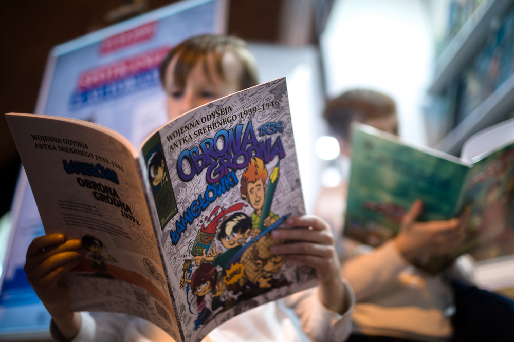 Hubert Ronek, twórca komiksowej serii IPN „Wojenna odyseja Antka Srebrnego” oraz „Aga, Adam i Hamlet na tropie tajemnic” rysuje i podpisuje – Targi Wydawców Katolickich w Warszawie, 23 kwietnia 2023. Fot. Sławek Kasper.