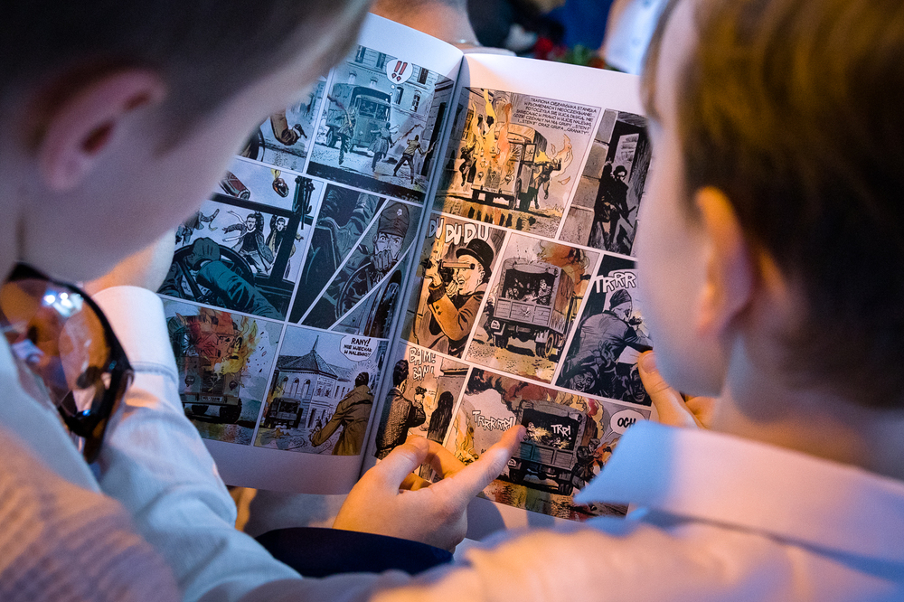 Hubert Ronek, twórca komiksowej serii IPN „Wojenna odyseja Antka Srebrnego” oraz „Aga, Adam i Hamlet na tropie tajemnic” rysuje i podpisuje – Targi Wydawców Katolickich w Warszawie, 23 kwietnia 2023. Fot. Sławek Kasper.