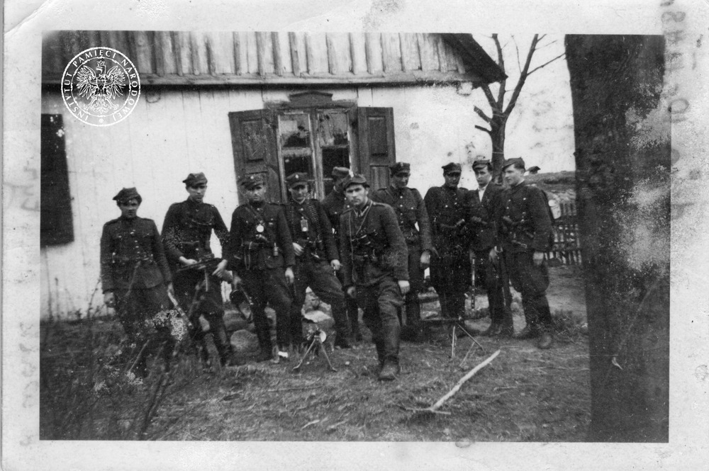 Oddział NZW pod dowództwem st. sierż. Mieczysława Dziemieszkiewcza ps. „Rój” (stoi przed szeregiem). Za nim stoją od lewej: Stanisław Okuniecki ps. „Kruk” (zastępca dowódcy) oraz Ildefons Tadeusz Żbikowski ps. „Tygrys” (dowódca patrolu). Zdjęcie wykonane przez Edmunda Kołakowskiego, wiosną 1948 r., na posesji Stanisława Obiedzińskiego w m. Pokojewo gm. Bartołdy. Fot. ze zbiorów AIPN