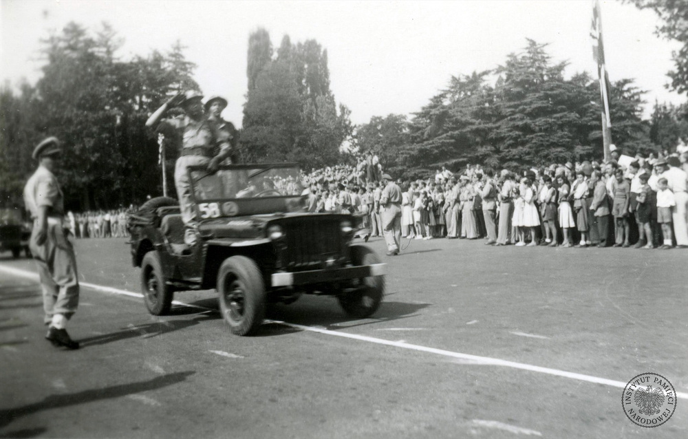 Samochód terenowy typu jeep (Willys MB lub Ford GPW) z dowódcą 4. Wołyńskiej Brygady Piechoty, wchodzącej w skład 5. Kresowej Dywizji Piechoty, płk. Stanisławem Sztarejko (salutuje) przejeżdża ulicą (Foro Buonaparte?) przed zamkiem Sforzów (wł. Castello Sforzesco) podczas defilady przed dowódcą 2. Korpusu Polskiego gen. dyw. Władysławem Andersem z okazji Święta Żołnierza. Mediolan, 15 VIII 1946 r. Autor: nieznany (fot. z zasobu IPN)