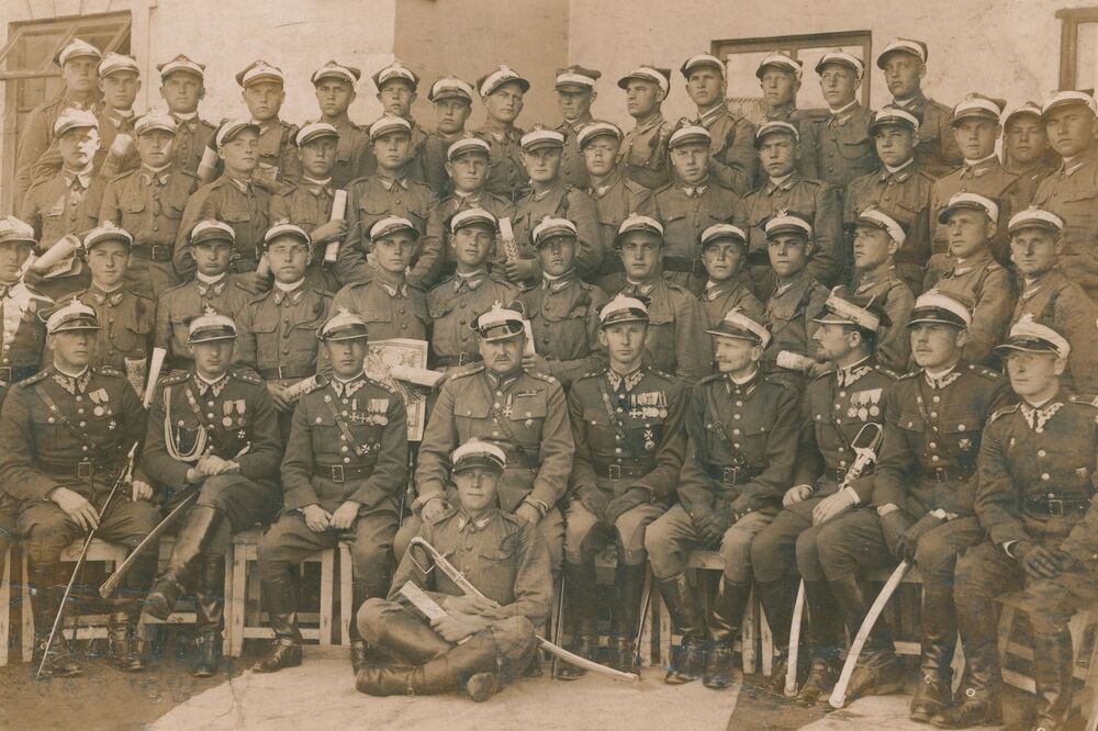 Zakończenie nauki w szkole podoficerskiej w 5. pułku strzelców konnych. W pierwszym rzędzie kadra oficerska pułku, powyżej strzelcy konni ze świadectwami ukończenia szkoły podoficerskiej oraz „Zarysami historji wojennej 5 pułku strzelców konnych” w rękach. Ludwik Kawik stoi trzeci z prawej w drugim rzędzie od dołu. Fot. archiwum rodzinne